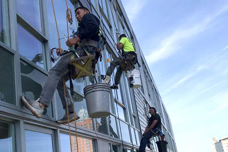 Snugs Services technicians performing professional high-rise window and exterior cleaning on a commercial building in Portland, OR using specialized rope access equipment. by Snugs Services