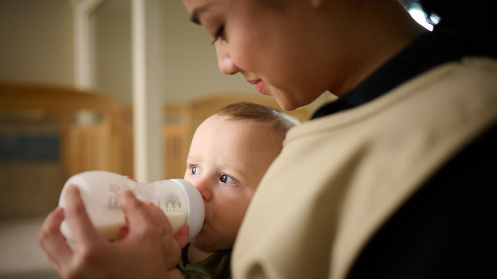 Primrose Schools infant care teacher bottle feeding newborn in nurturing early childhood classroom by Primrose School at Vista Ridge