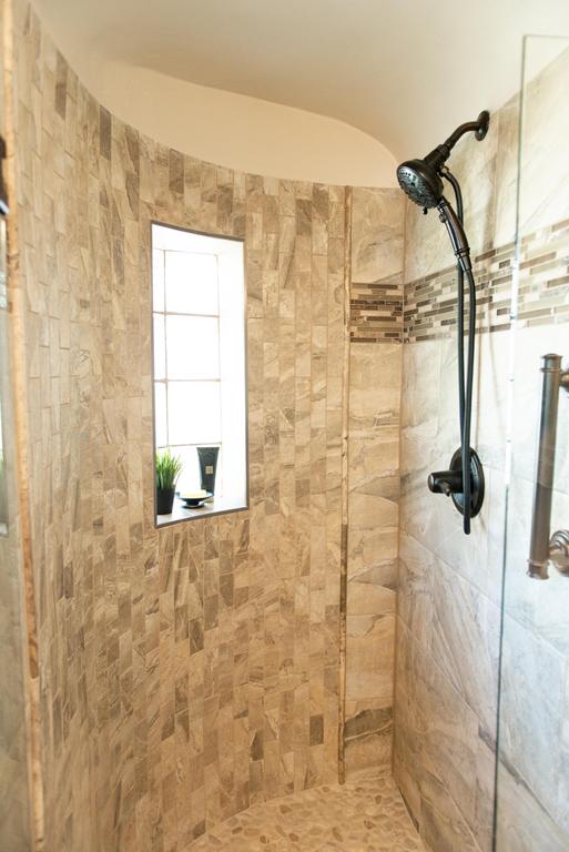 The shower floor is a hemisphere pebble mosaic tile in Antigua. The wall tile consists of a 12"x24" Emser Eurasia Chiara tile. by DreamMaker Bath & Kitchen