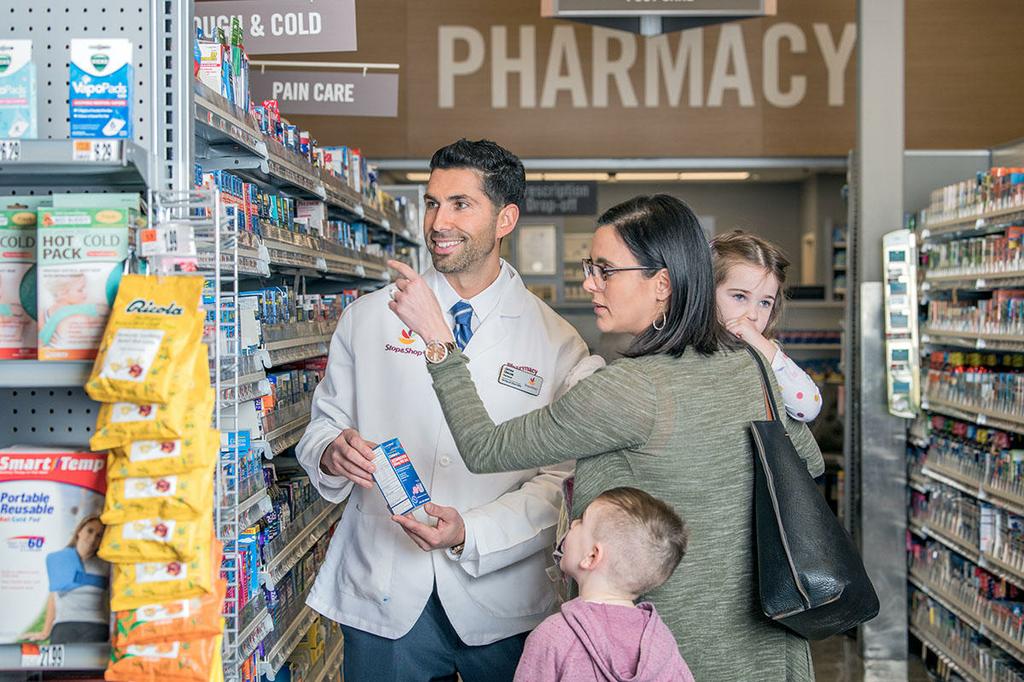 Customer with children asking advice from pharmacist in aisle by Stop & Shop