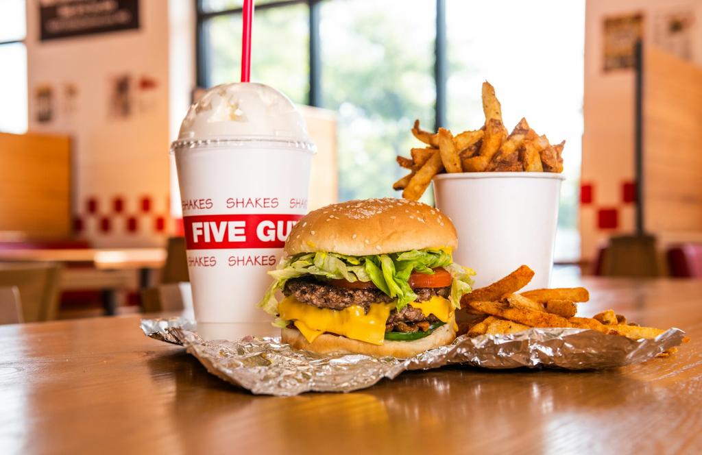 A Five Guys cheeseburger, milkshake and regular order of fries sits on a table inside a Five Guys restaurant. by Five Guys