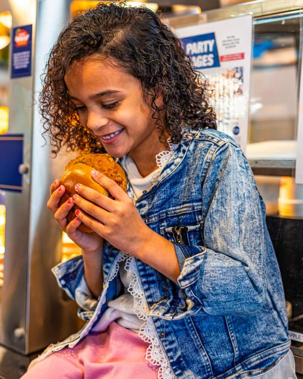 A guest enjoying a Krispy Krunchy Chicken sandwich, capturing the fresh, made-to-order experience inside the store. by Krispy Krunchy Chicken