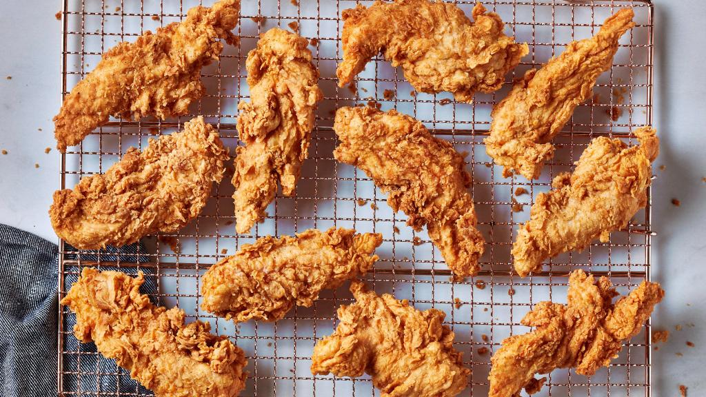 An assortment of freshly fried chicken pieces cooling on a rack, highlighting the golden, crunchy breading Krispy Krunchy Chicken is famous for. by Krispy Krunchy Chicken