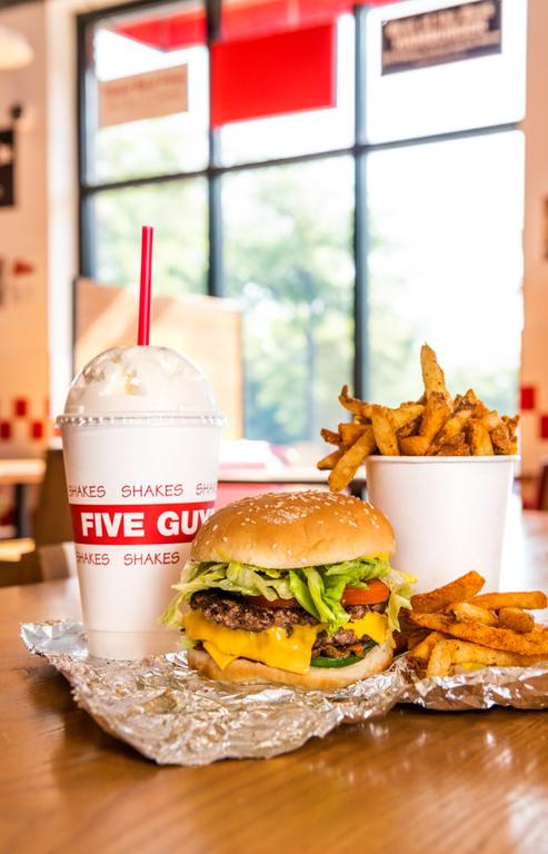 A Five Guys cheeseburger, milkshake and regular order of fries sits on a table inside a Five Guys restaurant. by Five Guys