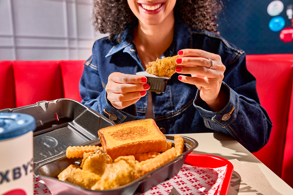 Customer enjoying Zaxbys lemon pepper chicken wings meal with Texas toast, fries, and ranch dipping sauce. by Zaxbys Chicken Fingers & Buffalo Wings